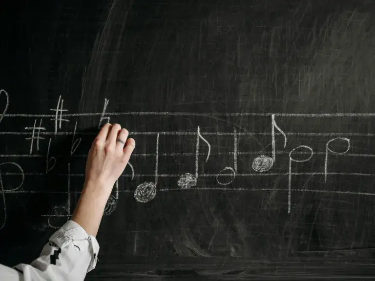 hand writing music notes on chalk board