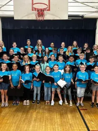 Choral students holding folders and smiling. 