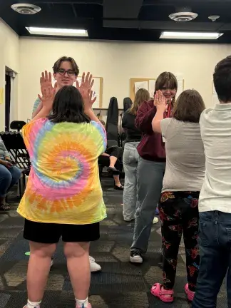 Students in a classroom facing each other and clapping hands.